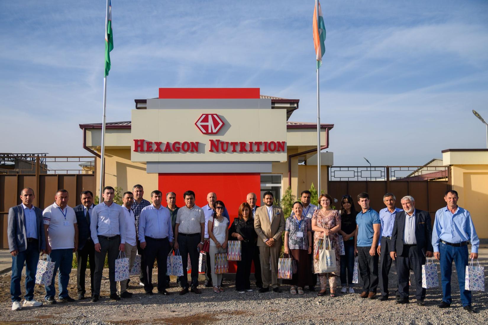 Group of people standing in front of the building with a sign Hexagon Nutrition on it