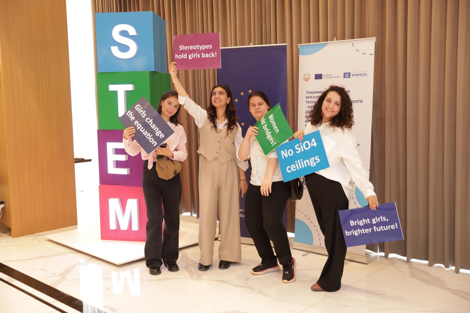 A group of young girls posing with different signs with messages to support girls education