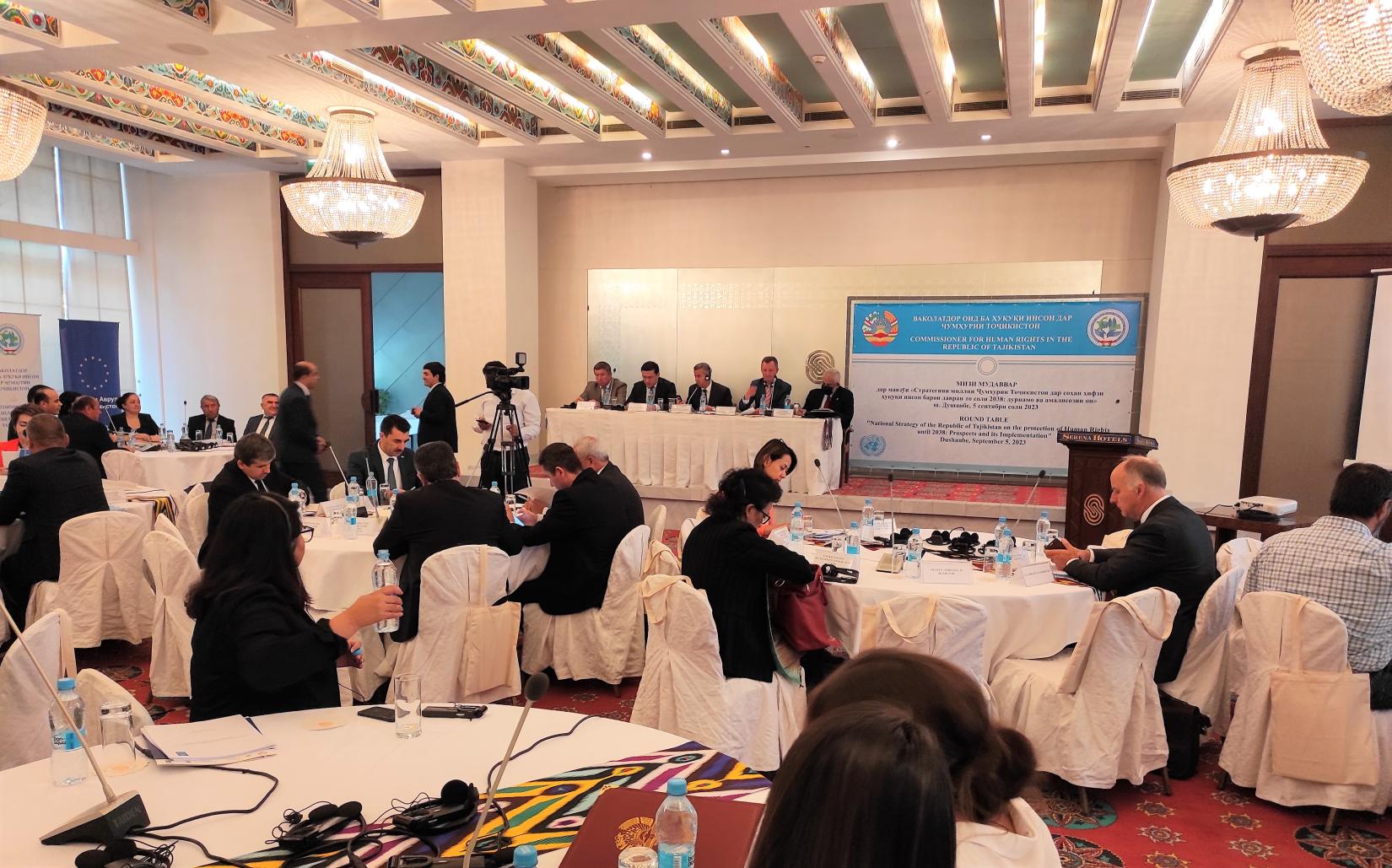 A group of people in a meeting room listening to the opening remarks